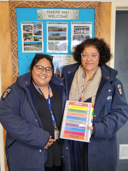 Phillipa and Mali hold up a Community Work Supervisor induction booklet