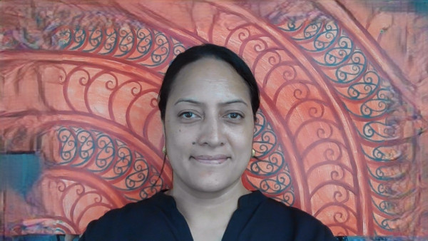 Case manager Sefrosa stands against a walll painted pink with red and blue korus